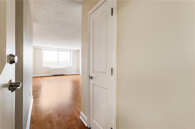 hall with hardwood / wood-style floors and a textured ceiling