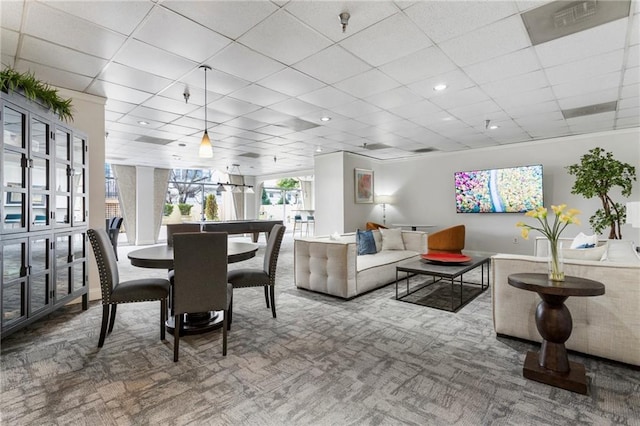 carpeted living room featuring a drop ceiling