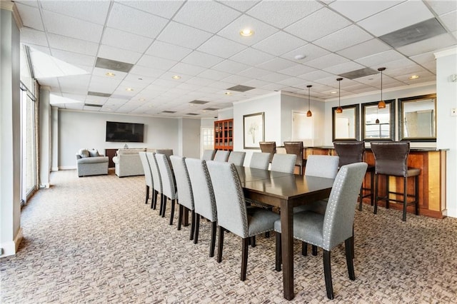 dining room featuring carpet flooring, bar, and a drop ceiling