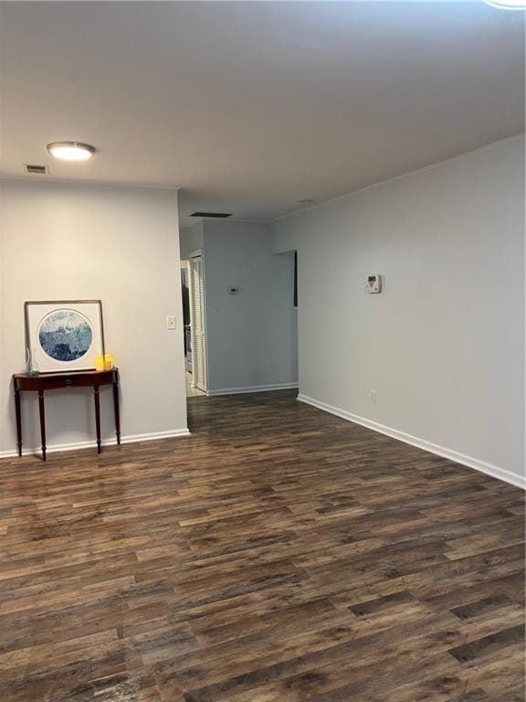 spare room with visible vents, baseboards, and dark wood finished floors
