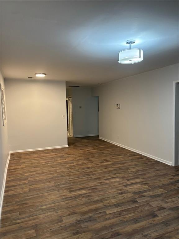 spare room with dark wood-type flooring and baseboards