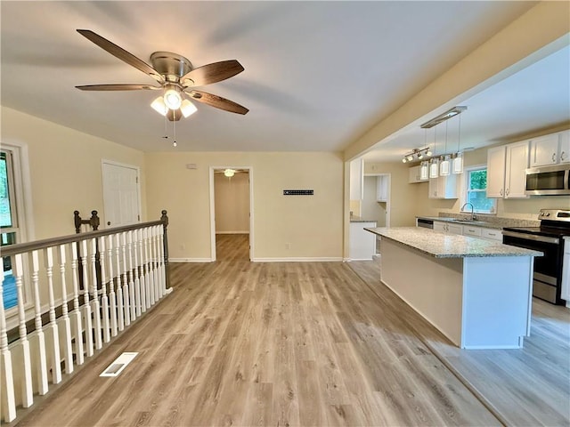 93 Mill Creek Rd, Hiram, GA 30141 - kitchen featuring stainless steel appliances, light stone counters, baseboards, a kitchen island, and light wood-style floors