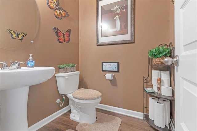 bathroom featuring baseboards, a sink, toilet, and wood finished floors