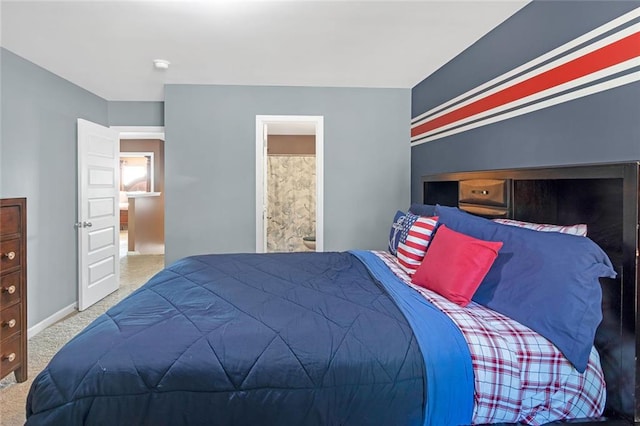 carpeted bedroom featuring ensuite bath and baseboards