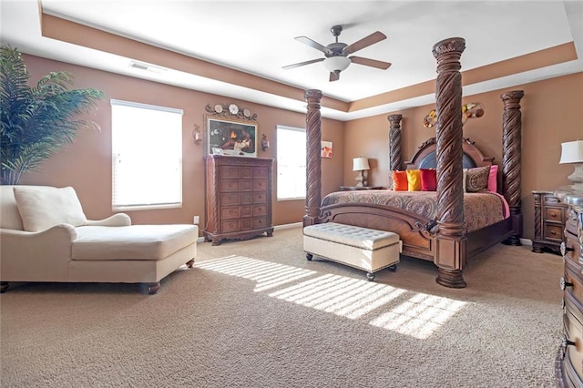 bedroom featuring a raised ceiling, visible vents, carpet flooring, ceiling fan, and baseboards