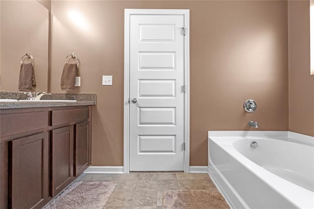 bathroom with a garden tub, vanity, and baseboards