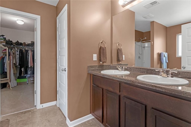 bathroom featuring a walk in closet, a sink, visible vents, and a shower stall