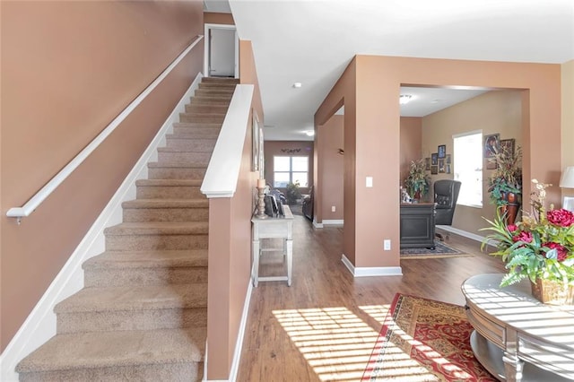 staircase featuring wood finished floors and baseboards