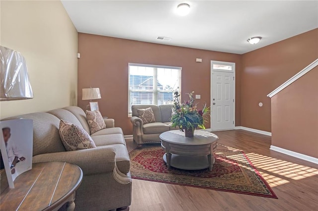 living room with visible vents, baseboards, and wood finished floors