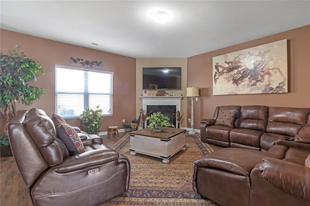 living room featuring a fireplace, wood finished floors, visible vents, and baseboards