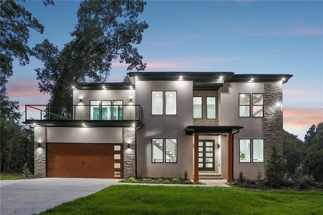 modern home featuring a lawn, a balcony, and a garage