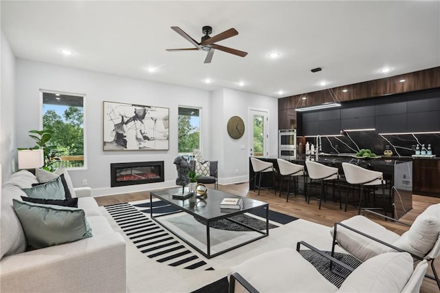 living room with plenty of natural light, light wood-type flooring, and ceiling fan