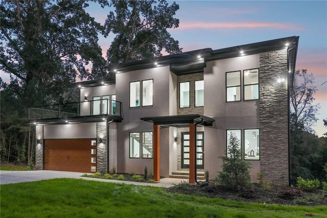 contemporary house with a balcony, a garage, and a yard