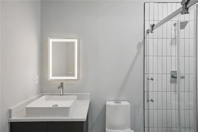 bathroom featuring vanity, a shower with door, and toilet