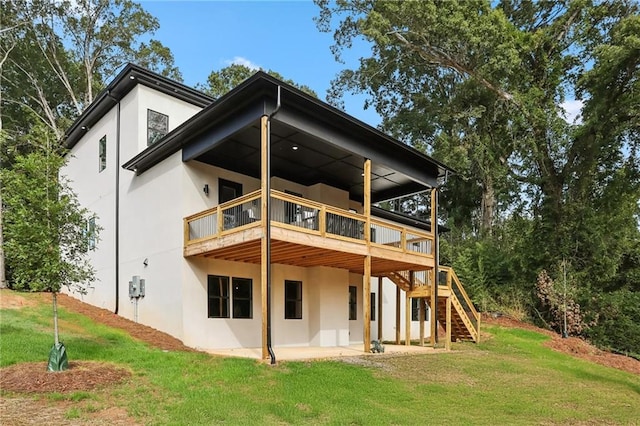 rear view of property featuring a deck, a lawn, and a patio area