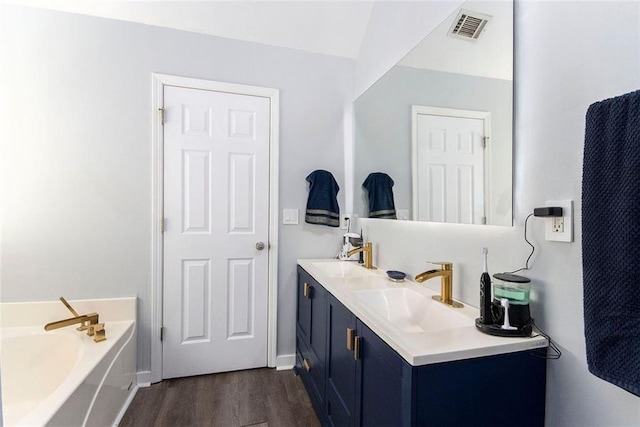 bathroom featuring wood-type flooring, vanity, and a tub