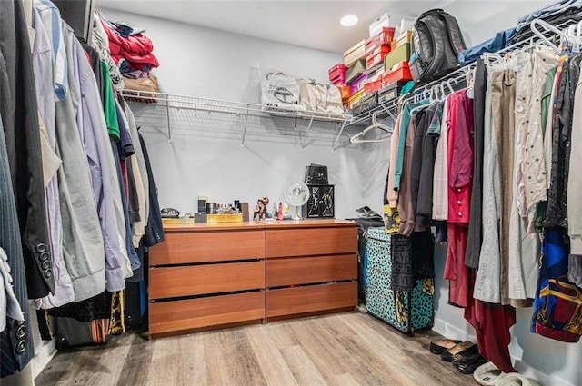 walk in closet with light hardwood / wood-style flooring