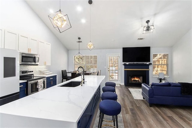 kitchen with a kitchen island with sink, sink, pendant lighting, and stainless steel appliances