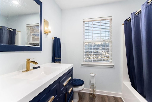 full bathroom featuring hardwood / wood-style flooring, vanity, shower / bath combination with curtain, and toilet