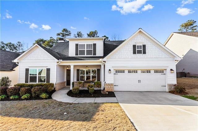 craftsman-style home featuring a shingled roof, concrete driveway, a porch, and central air condition unit