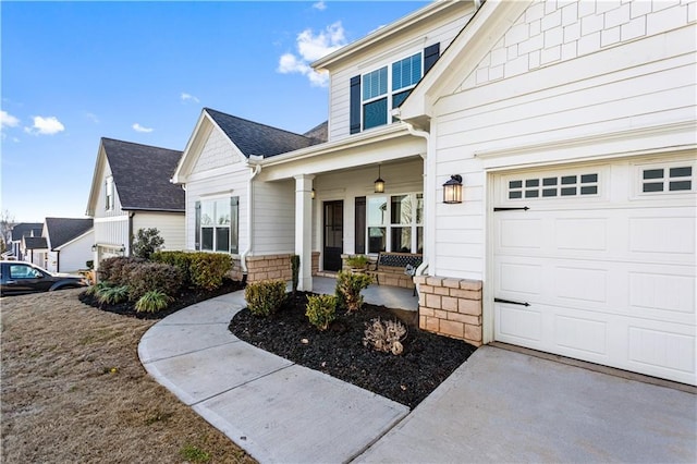 doorway to property featuring a garage, a porch, and a shingled roof