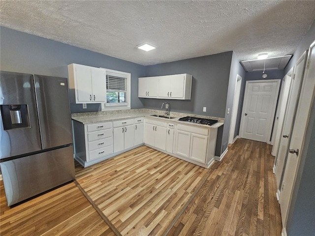 1150 Goldsmith Rd, Stone Mountain, GA 30083 - kitchen featuring appliances with stainless steel finishes, a sink, wood finished floors, white cabinets, and a textured ceiling
