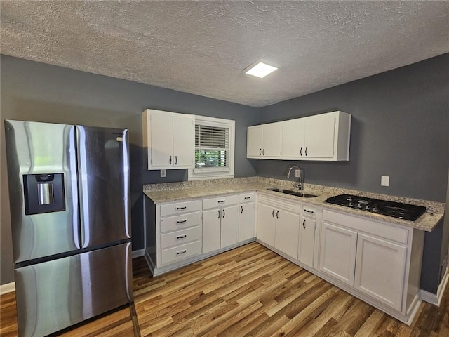 1150 Goldsmith Rd, Stone Mountain, GA 30083 - kitchen with stainless steel appliances, a sink, light wood-style flooring, white cabinets, and a textured ceiling