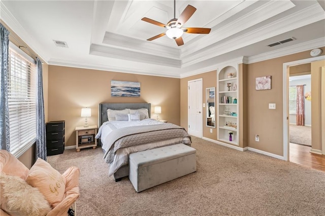 carpeted bedroom featuring baseboards, visible vents, a raised ceiling, and crown molding