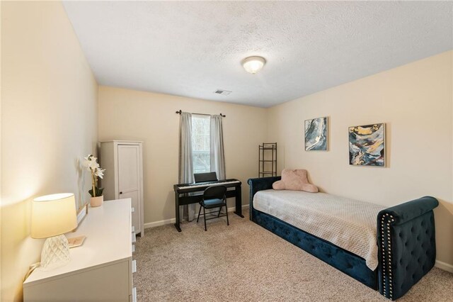 bedroom featuring baseboards, visible vents, a textured ceiling, and light colored carpet