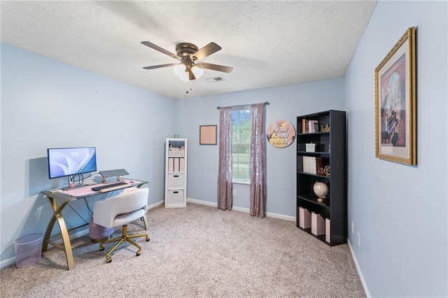 office featuring baseboards, visible vents, a ceiling fan, carpet, and a textured ceiling