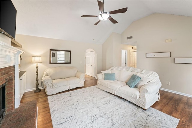 living area featuring baseboards, visible vents, a ceiling fan, wood finished floors, and a brick fireplace