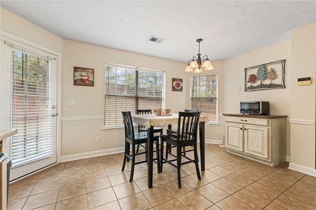 dining area featuring light tile patterned floors, baseboards, visible vents, and a notable chandelier