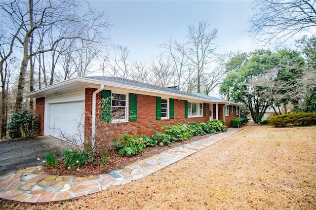 ranch-style home featuring driveway, brick siding, and an attached garage