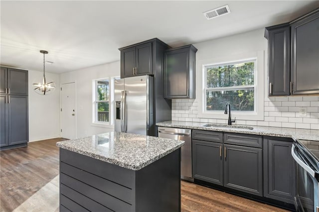 kitchen featuring decorative light fixtures, sink, a center island, stainless steel appliances, and dark wood-type flooring