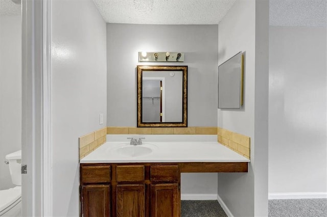 bathroom featuring vanity, toilet, and a textured ceiling