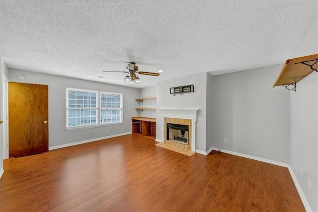 unfurnished living room with hardwood / wood-style floors, a fireplace, ceiling fan, and a textured ceiling