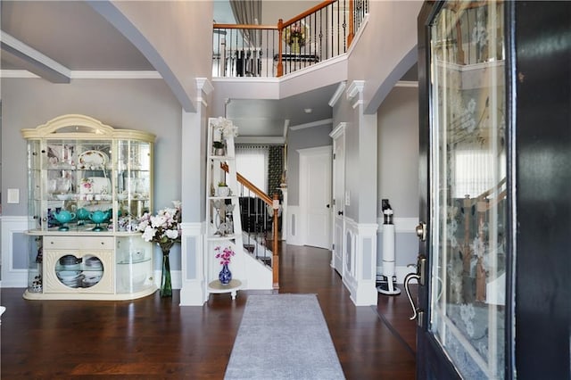 entryway featuring ornamental molding, decorative columns, dark hardwood / wood-style floors, and a towering ceiling