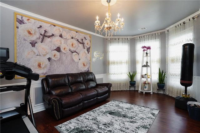 living room with crown molding, dark wood-type flooring, and a chandelier