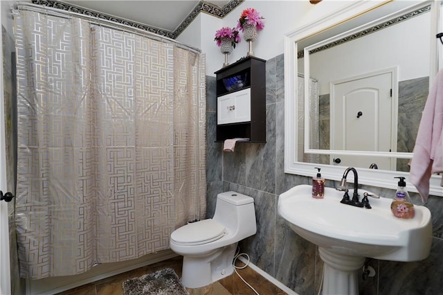 bathroom with toilet, a shower with shower curtain, and tile walls