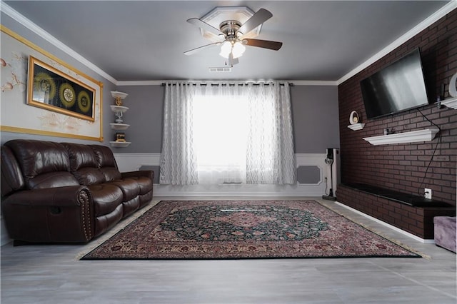 living room with light hardwood / wood-style flooring, crown molding, brick wall, and ceiling fan