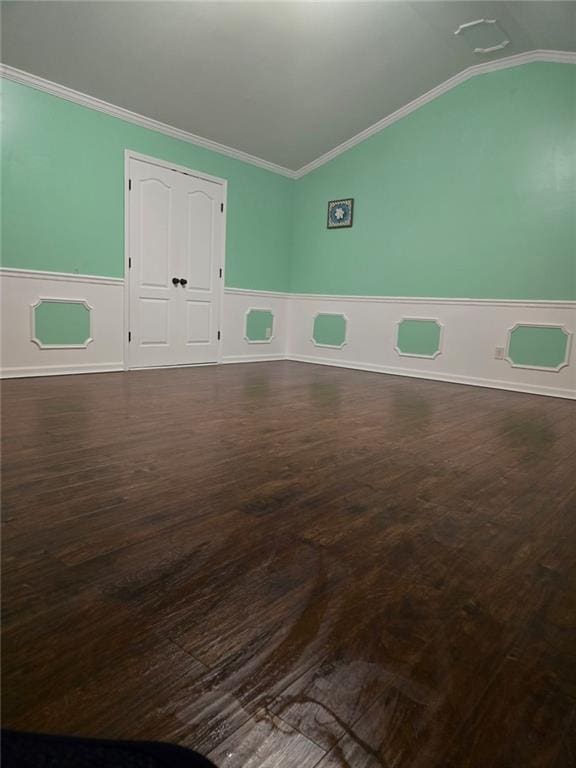 empty room featuring crown molding, vaulted ceiling, and dark wood-type flooring