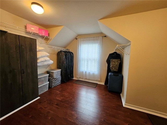 additional living space featuring dark wood-type flooring and vaulted ceiling