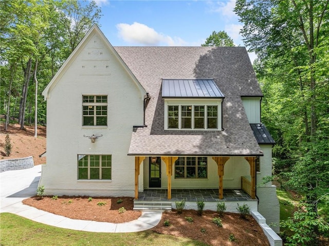 view of front of home with a standing seam roof, a porch, a shingled roof, and metal roof