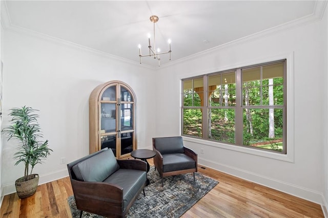 living area featuring a chandelier, baseboards, ornamental molding, and plenty of natural light