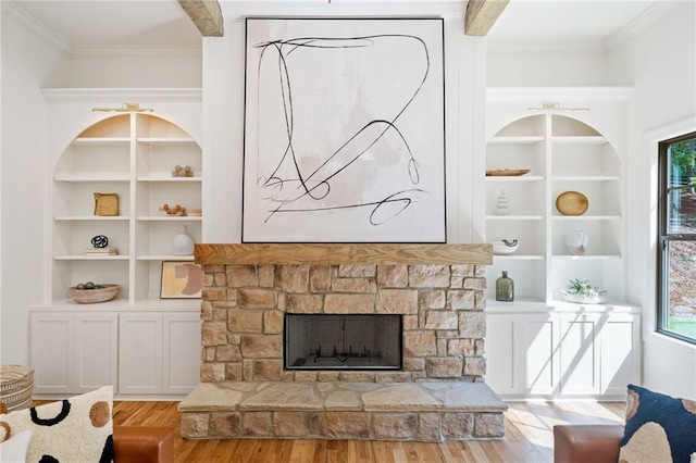 living room featuring wood finished floors, healthy amount of natural light, ornamental molding, built in features, and a fireplace