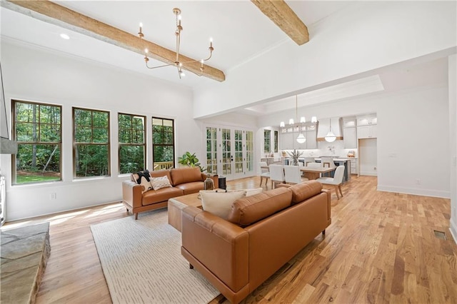 living room with a chandelier, beam ceiling, and light wood-type flooring