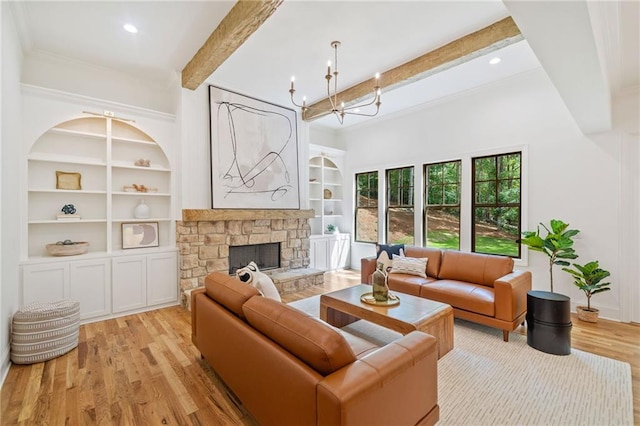 living room featuring built in shelves, light wood-style floors, beam ceiling, a fireplace, and a chandelier