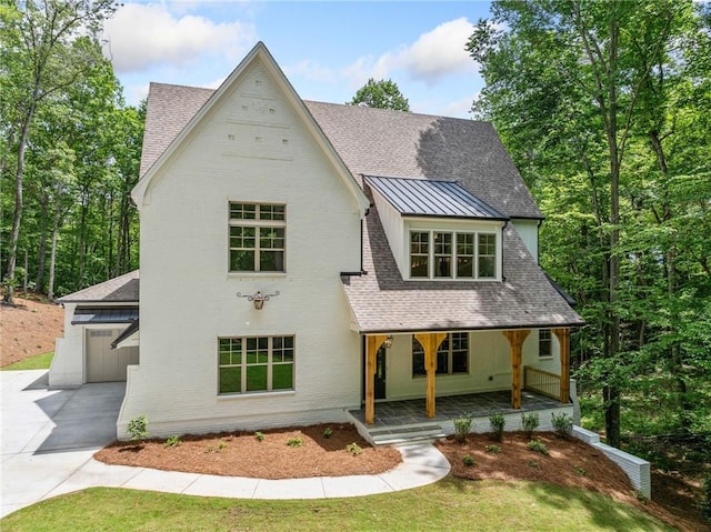 view of front of property with a porch, driveway, a standing seam roof, and a shingled roof