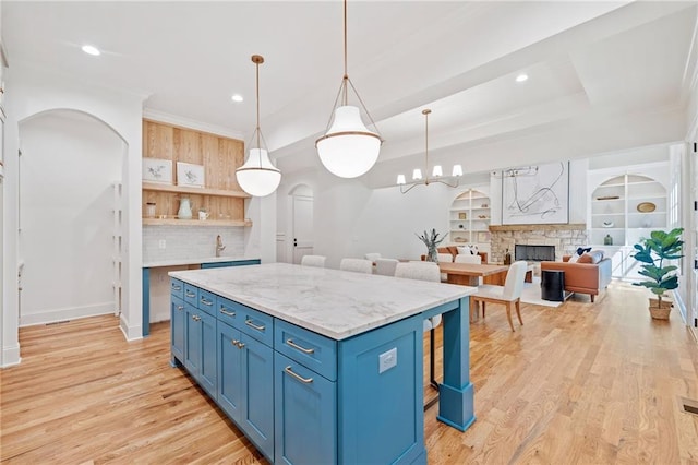 kitchen with blue cabinetry, arched walkways, a center island, light wood-style floors, and recessed lighting