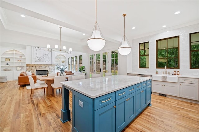 kitchen featuring a sink, light wood-style flooring, a fireplace, recessed lighting, and a kitchen island